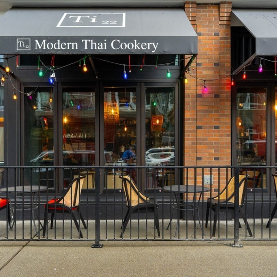 Ti 22 Modern Thai Cookery storefront with outdoor seating, black awnings, and colorful string lights.